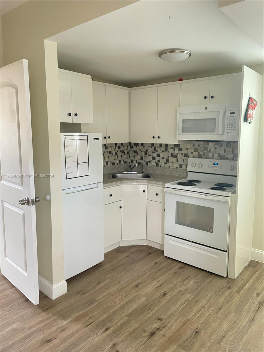 a kitchen with white cabinets and white appliances