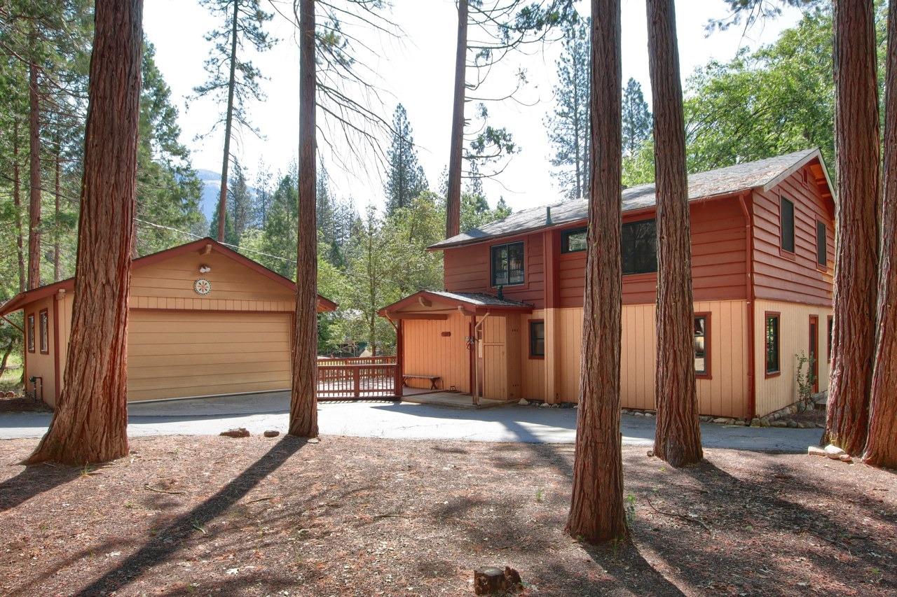 a view of a house with a yard and large tree