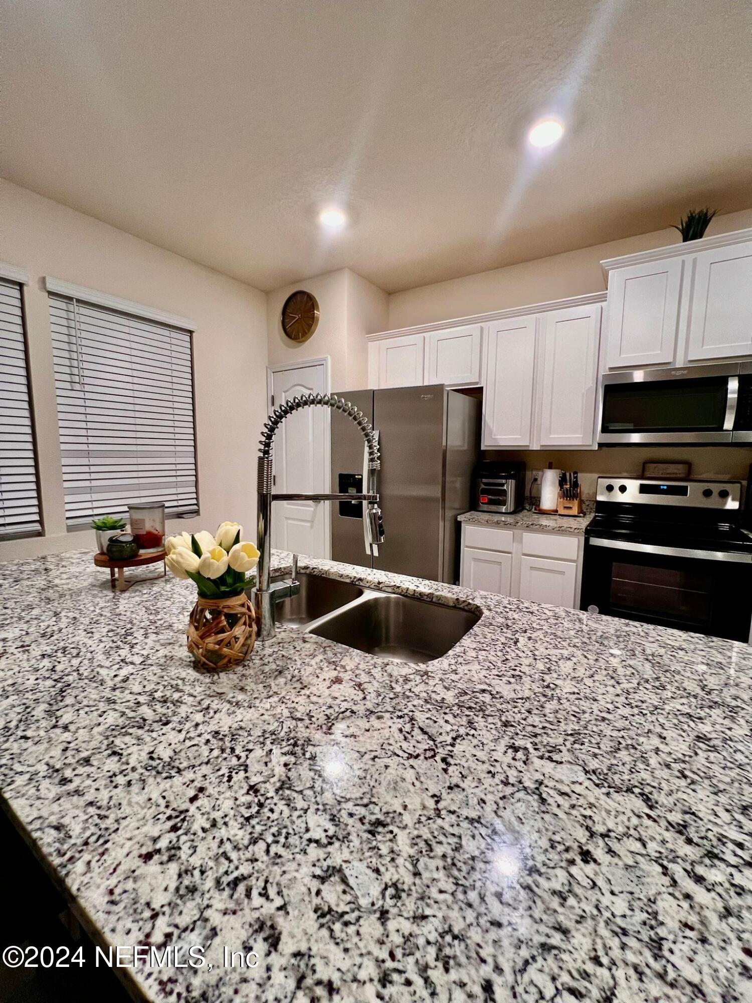 a kitchen with sink a refrigerator and chairs