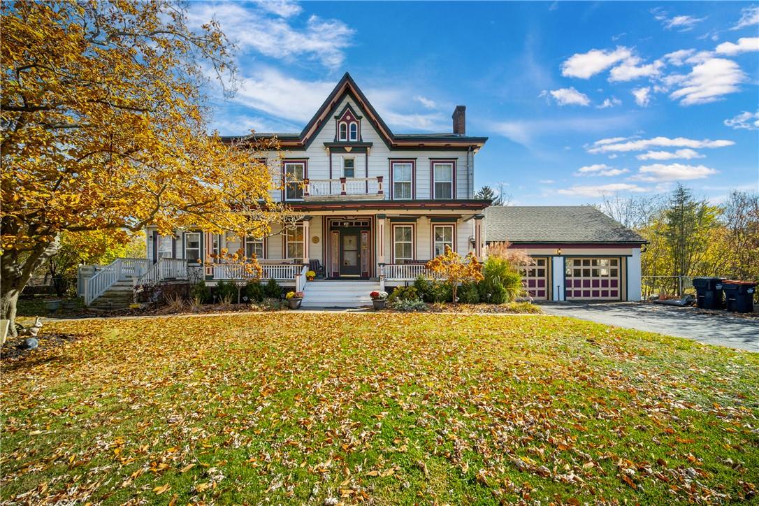 Victorian-style house featuring a garage, a front lawn, and a porch