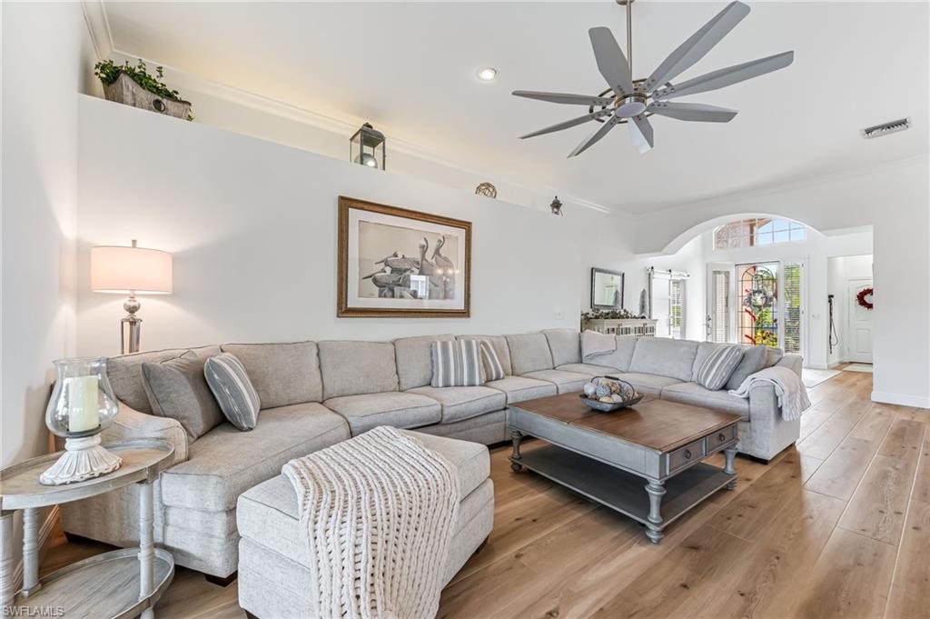 a living room with furniture a ceiling fan a lamp and a window