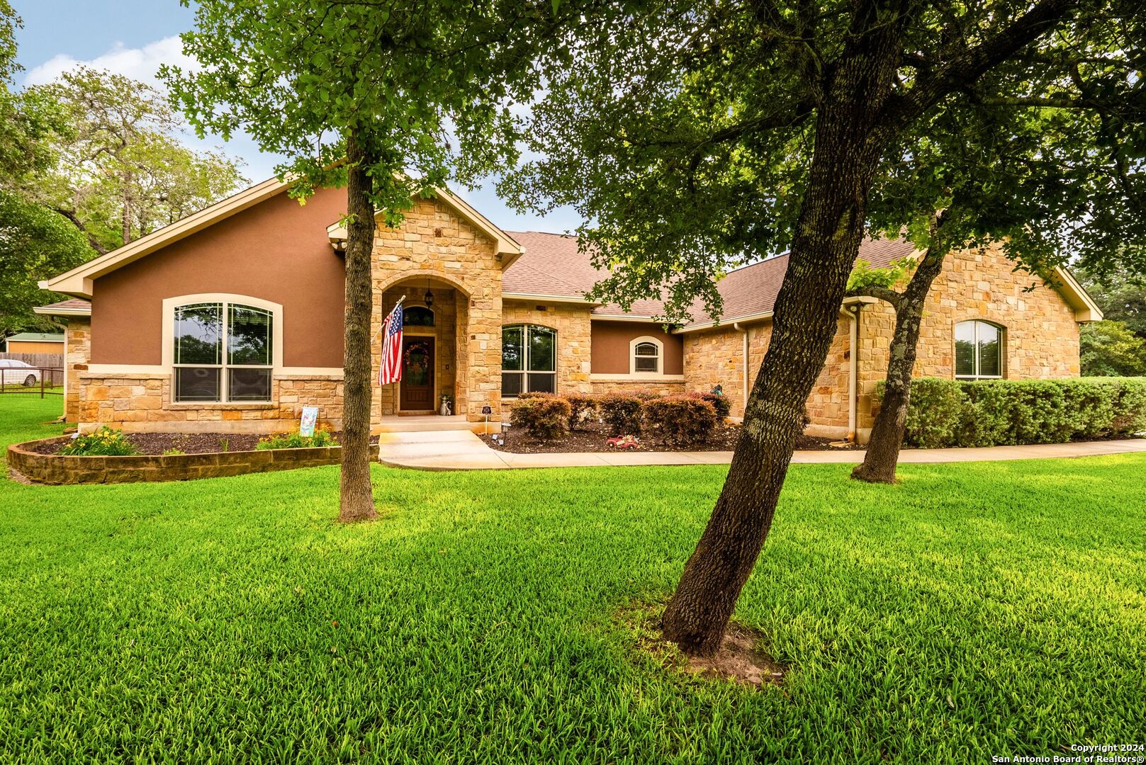 a front view of a house with a garden and trees