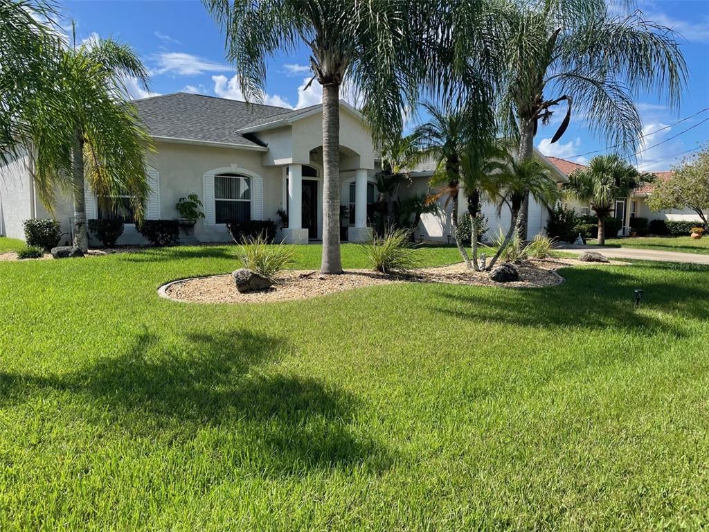 a view of a house with a yard and palm trees