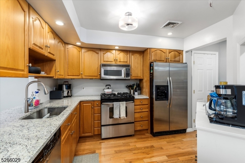 a kitchen with stainless steel appliances granite countertop a refrigerator a sink and a stove