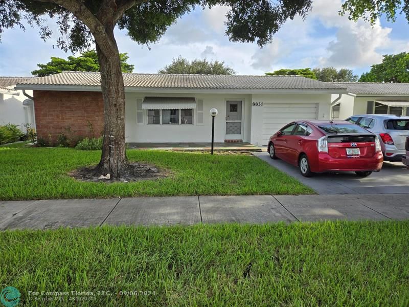 a front view of a house with a garden and parking