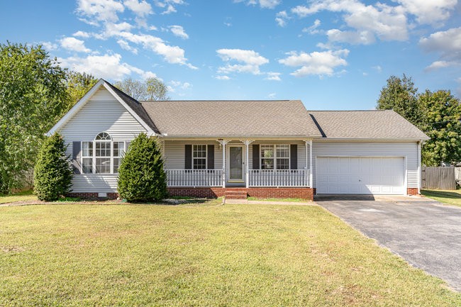 a front view of house with yard and trees in the background