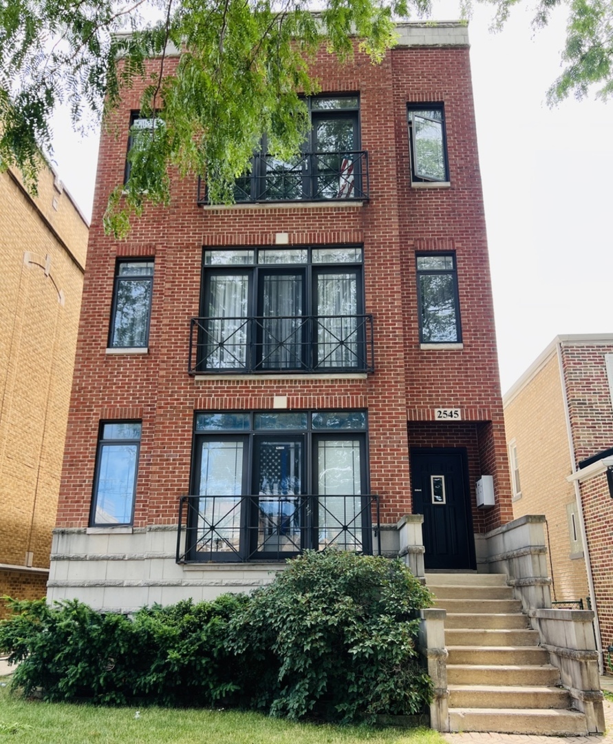 a view of a brick building with many windows and a yard