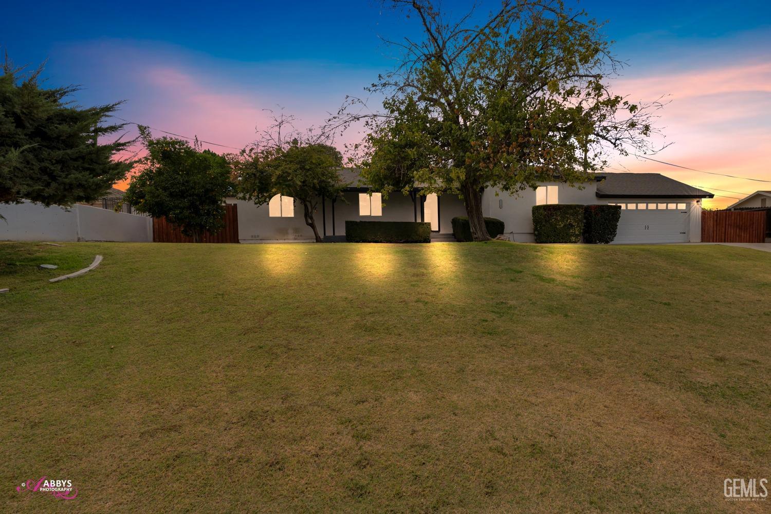 a front view of a house with a yard and a large tree