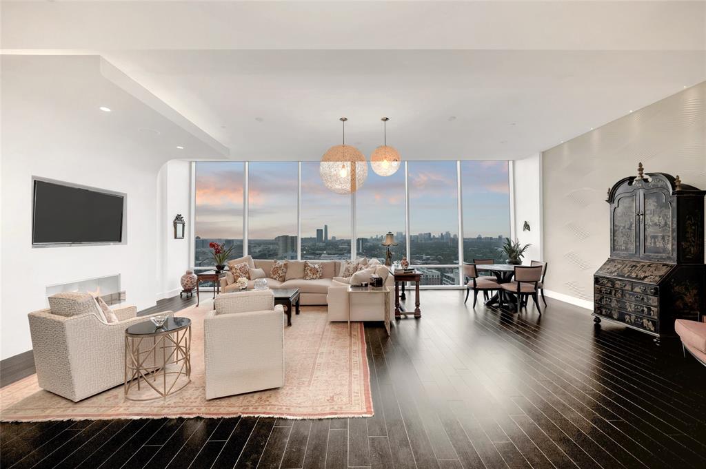 [Living Room]Sophisticated, Modern style enhances this light-filled unit in one of Houston’s most distinctive residential buildings. Open floor-plan, designed for easy entertaining and elegant daily living, features 10-ft ceilings, ebony-tone wood floors, and soft white and gray palette throughout. Note cantilevered wall in the living room surrounding a linear ethanol fireplace.