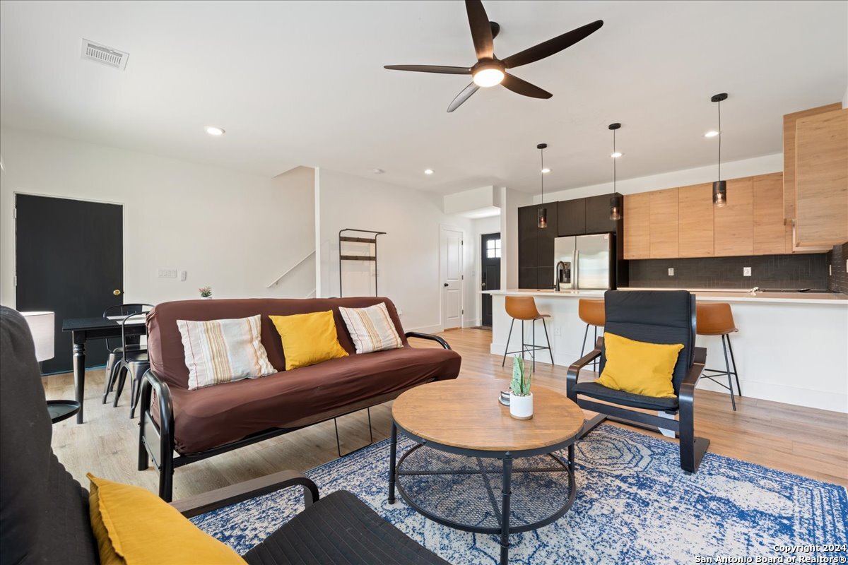 a living room with furniture kitchen view and a wooden floor