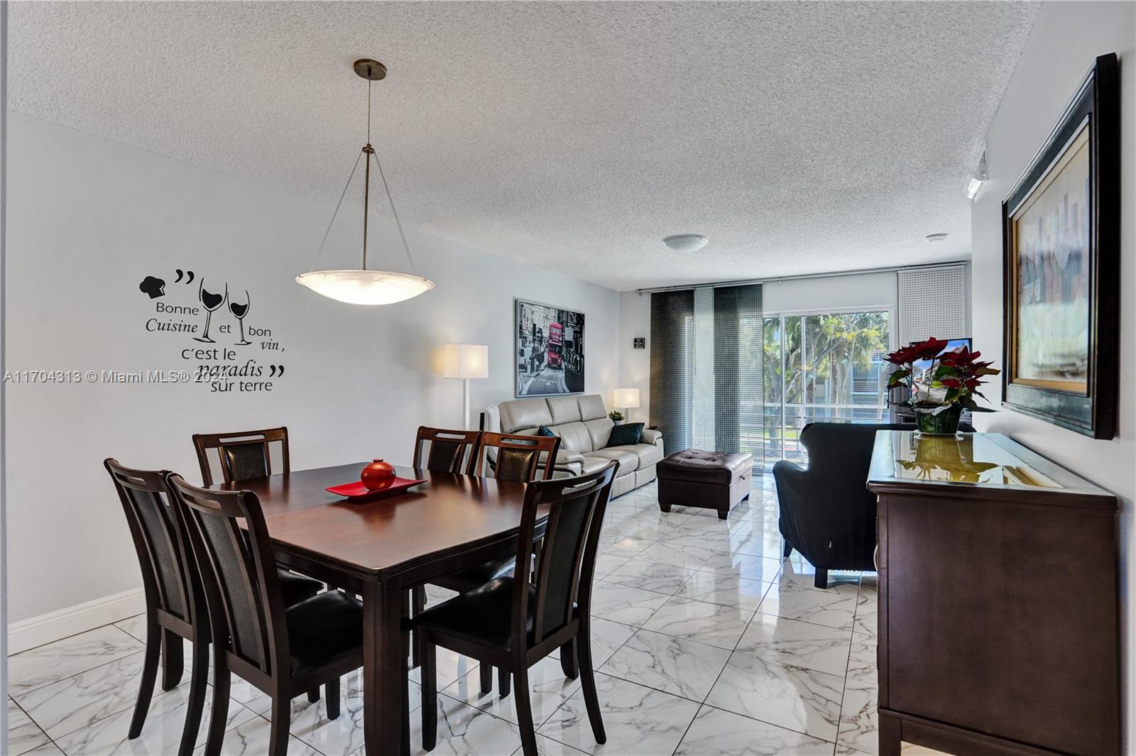 a view of a dining room and livingroom with furniture wooden floor a rug a potted plant and a chandelier