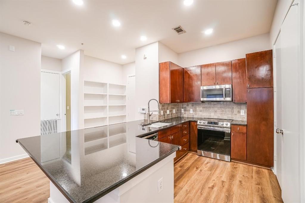 a kitchen with kitchen island granite countertop a sink and a stove top oven with wooden floor