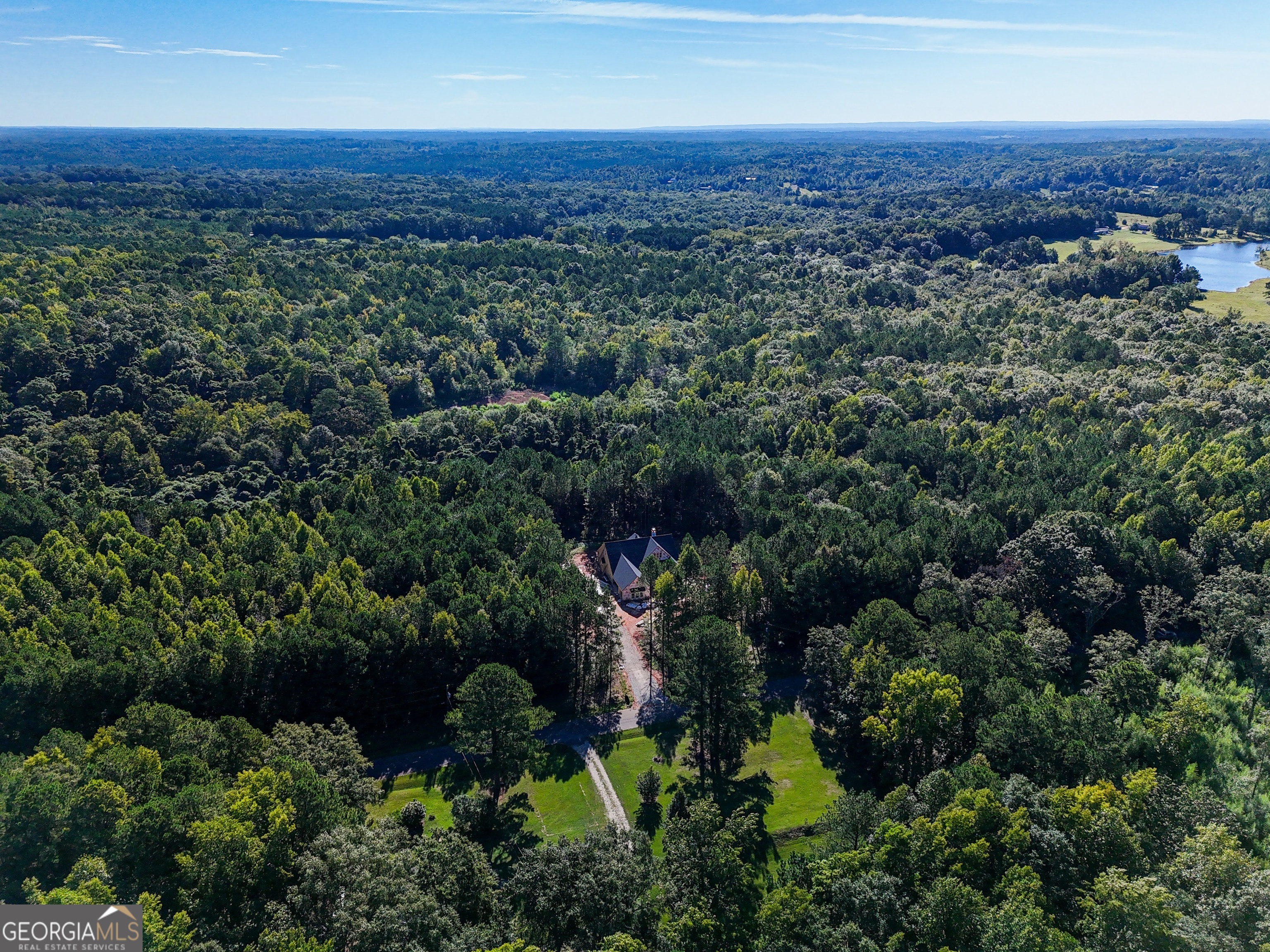 an aerial view of residential house with outdoor space and trees all around