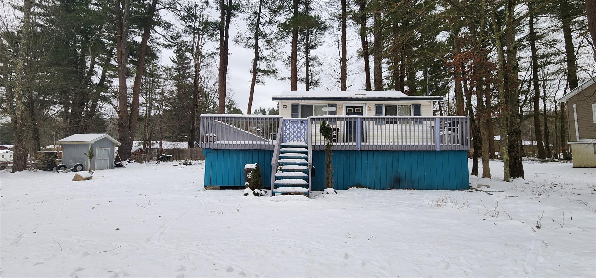 Snow covered property featuring a storage unit and a wooden deck