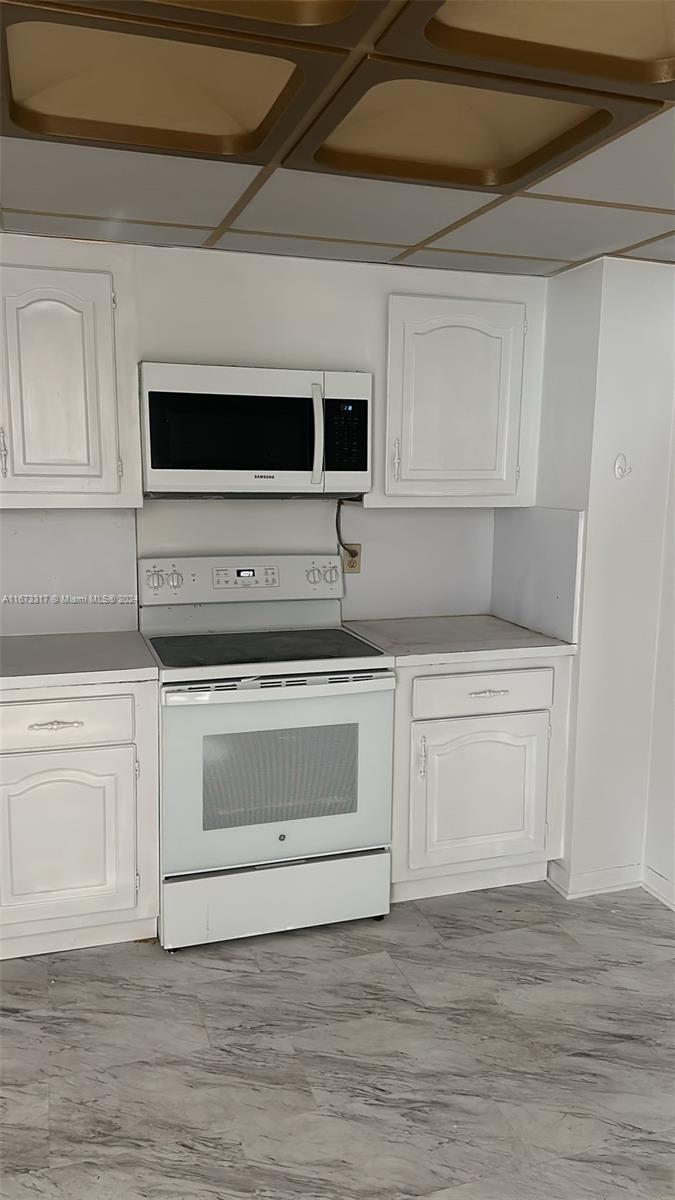 a kitchen with granite countertop white cabinets and stainless steel appliances