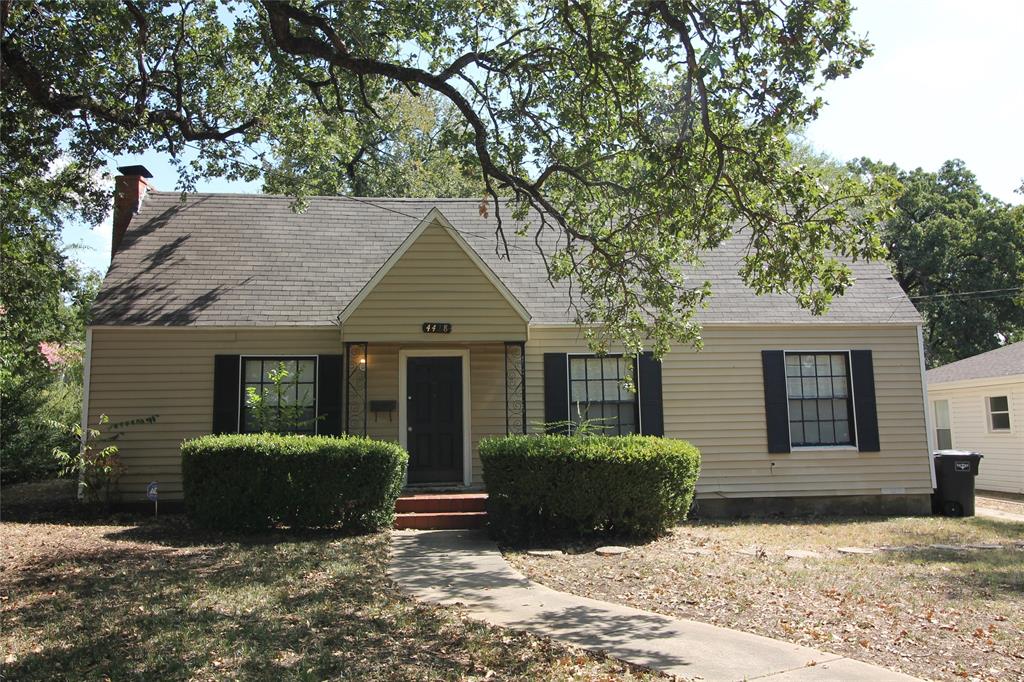 a view of a house with a yard and large tree