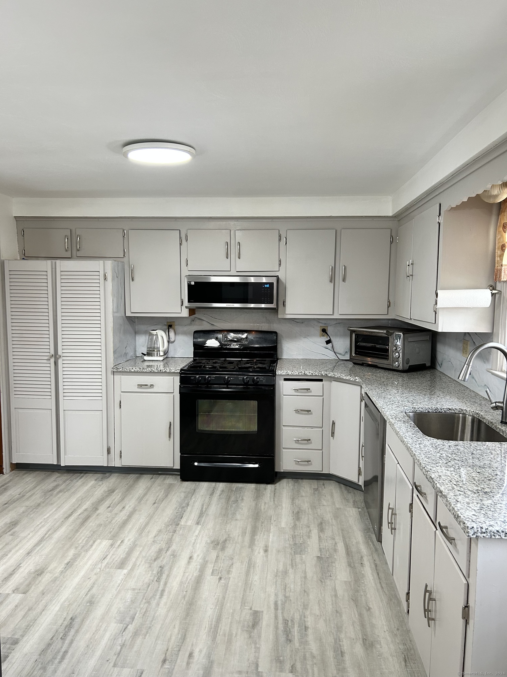 a kitchen with a stove white cabinets and sink