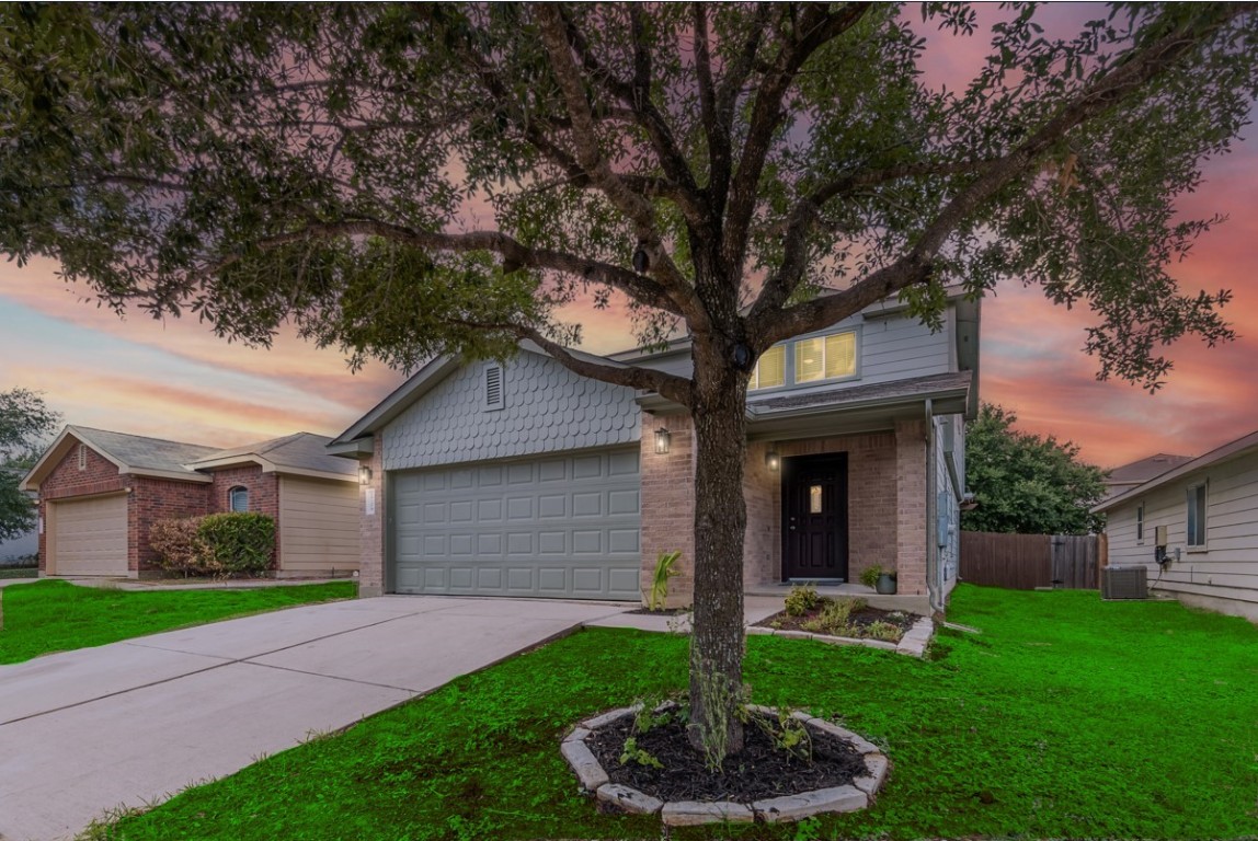 a front view of a house with a yard and tree