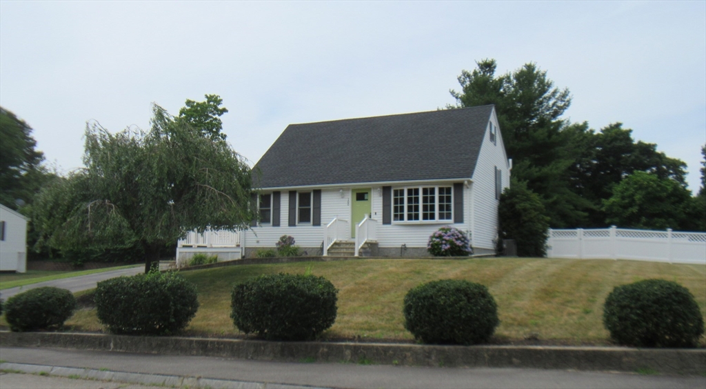 a view of house with yard and trees in the background