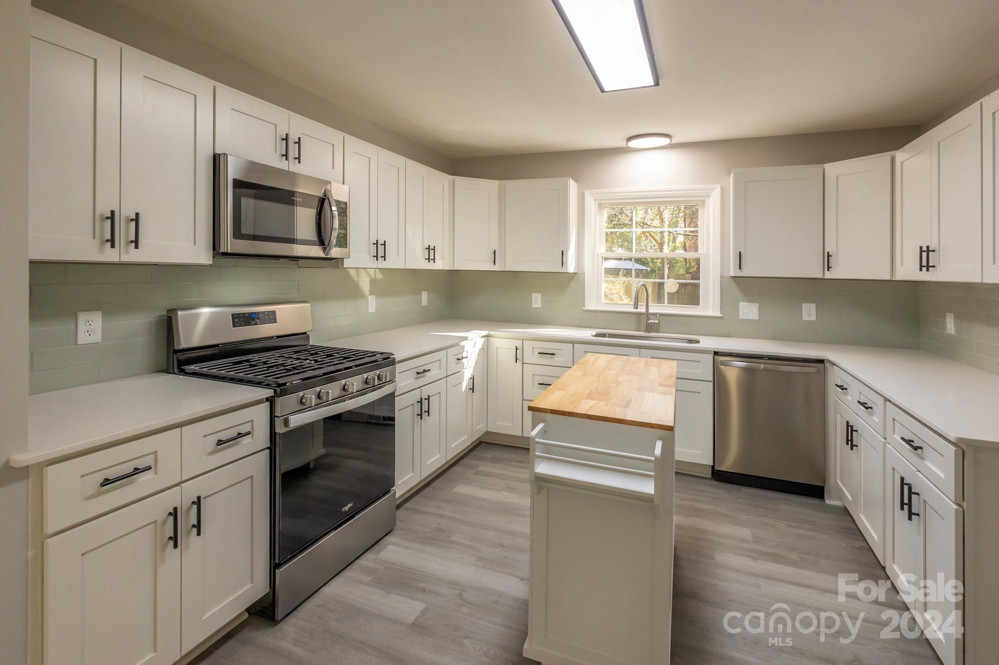 a kitchen with cabinets stainless steel appliances and a window