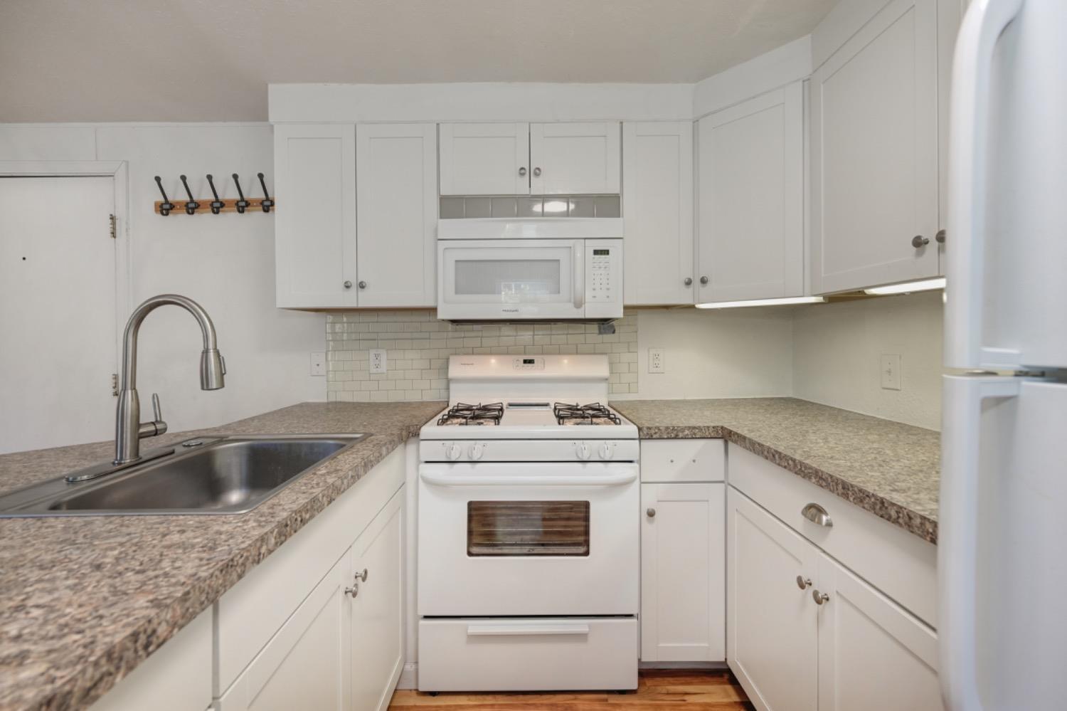 a kitchen with granite countertop white cabinets and white appliances