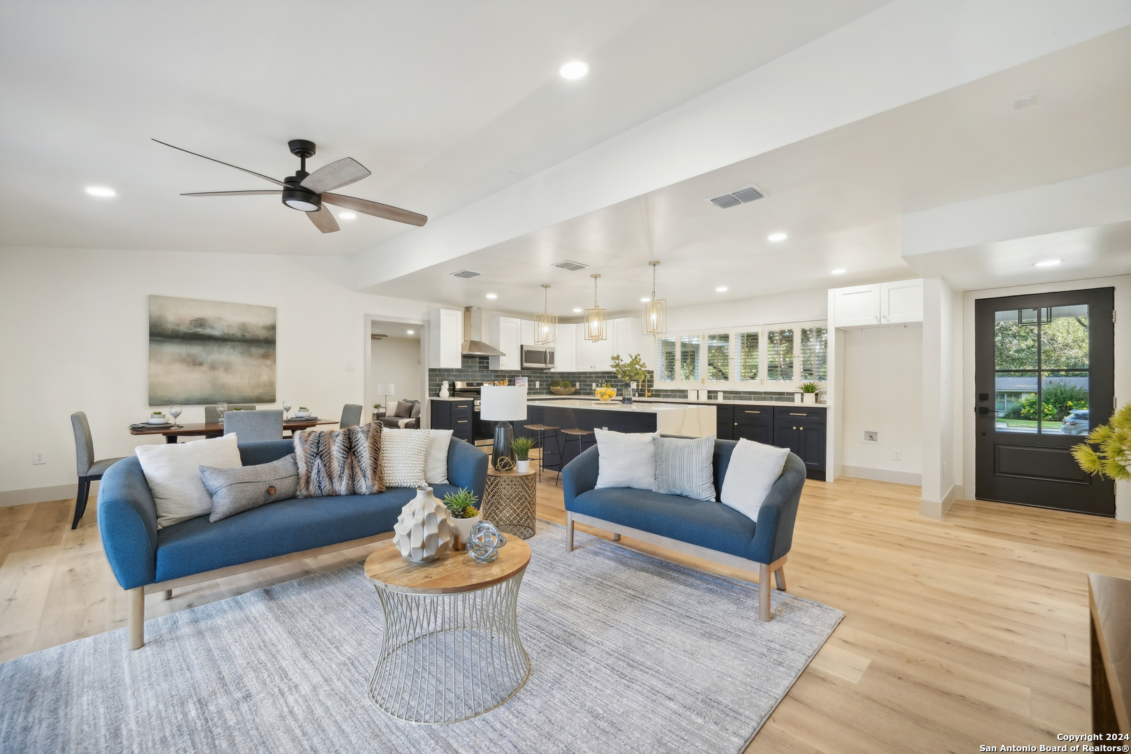 a living room with furniture kitchen view and a wooden floor