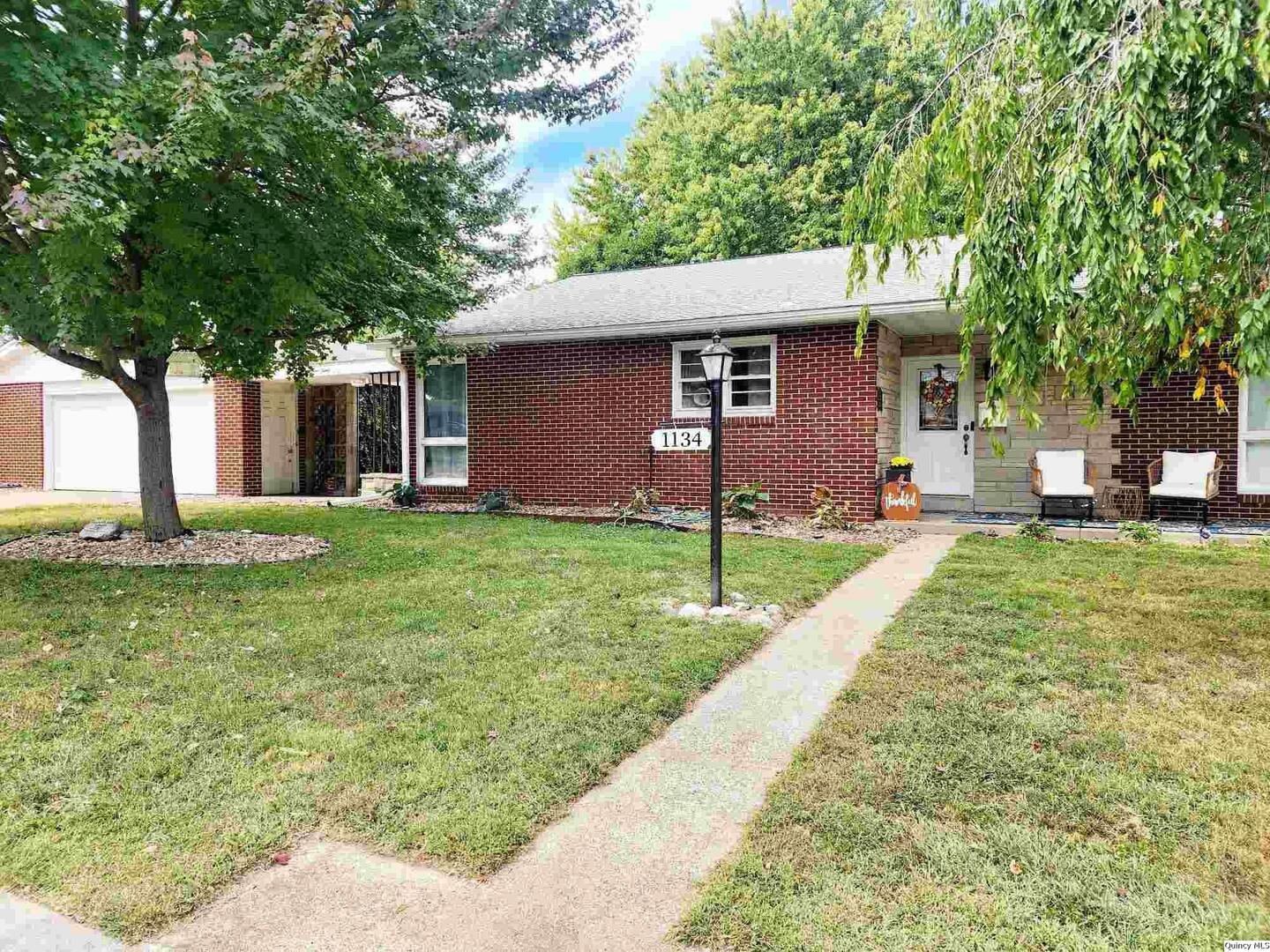 a front view of a house with a yard and trees