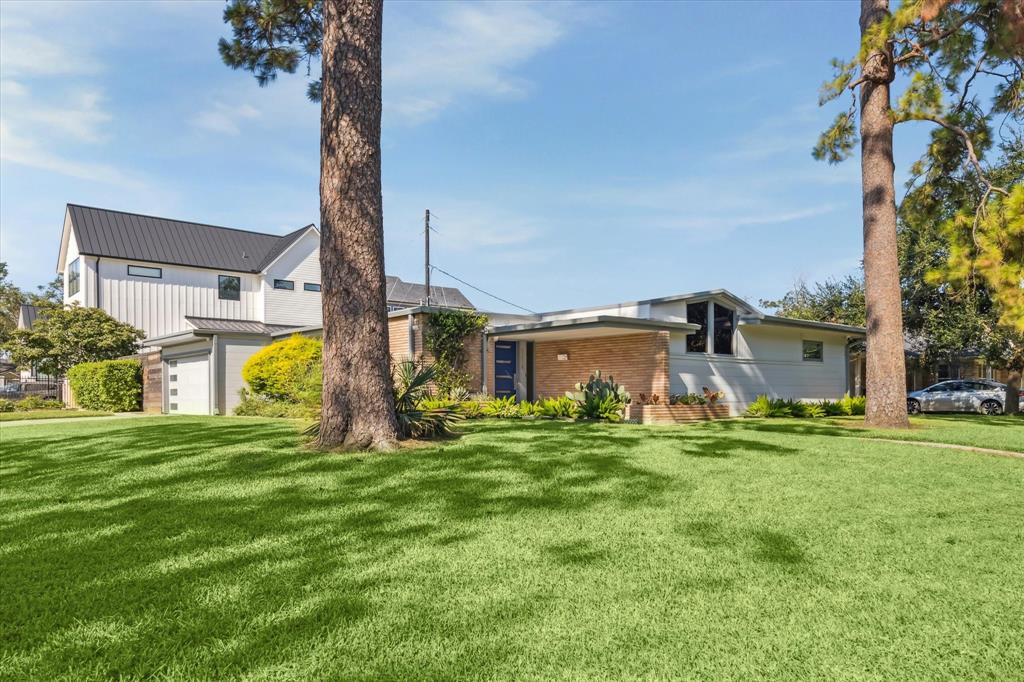 a house view with a big yard and large trees