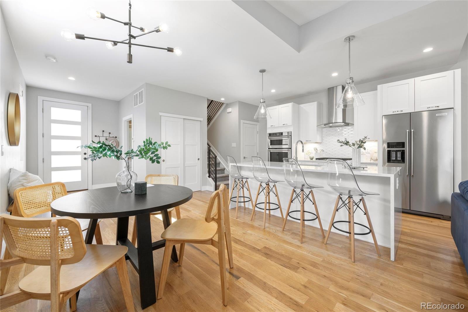 a kitchen with stainless steel appliances kitchen island granite countertop a dining table chairs and white cabinets