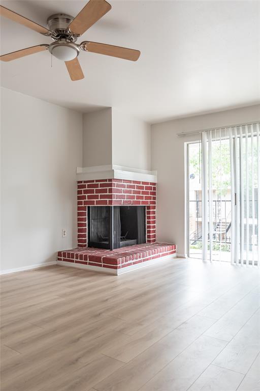 a view of an empty room with wooden floor and a fireplace