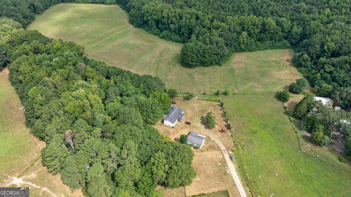 an aerial view of residential house with outdoor space and trees all around