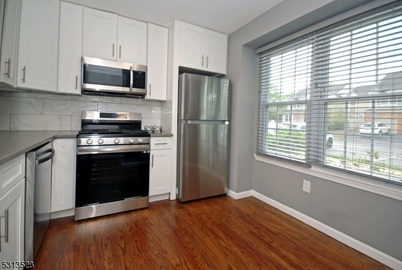 a kitchen with a wooden floor stainless steel appliances and window