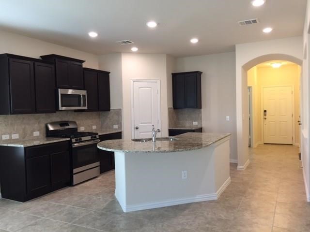 a view of a kitchen with a sink and dishwasher a stove top oven with wooden floor