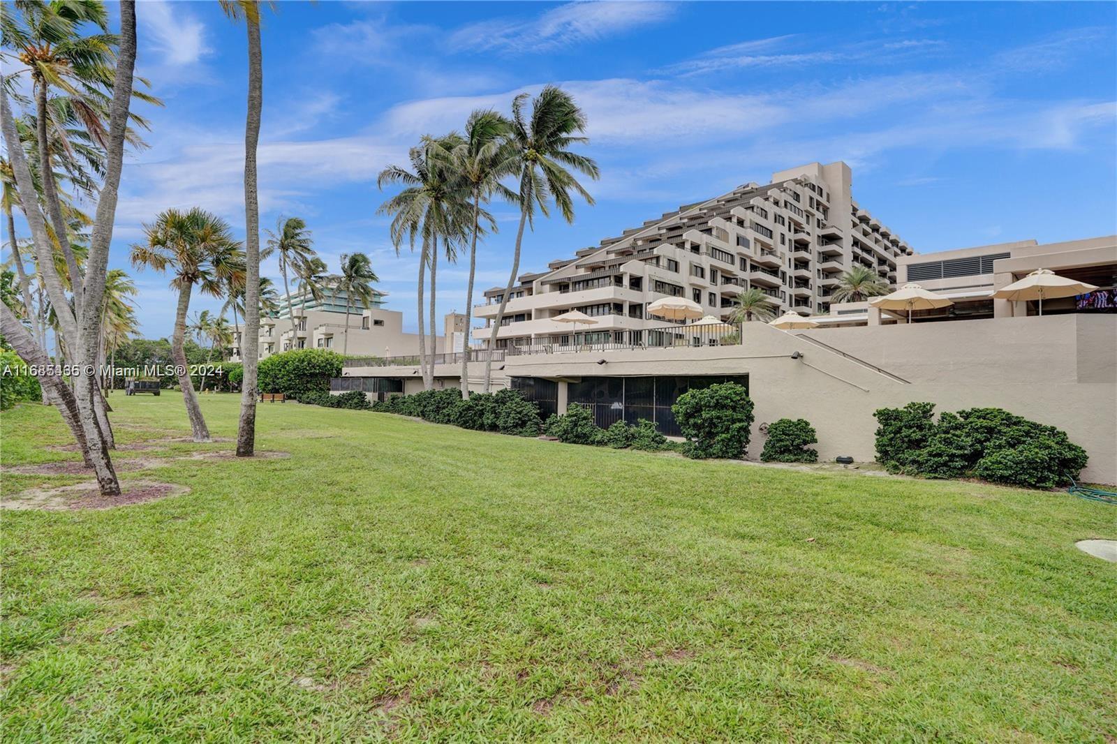 a view of a house with a yard and palm trees