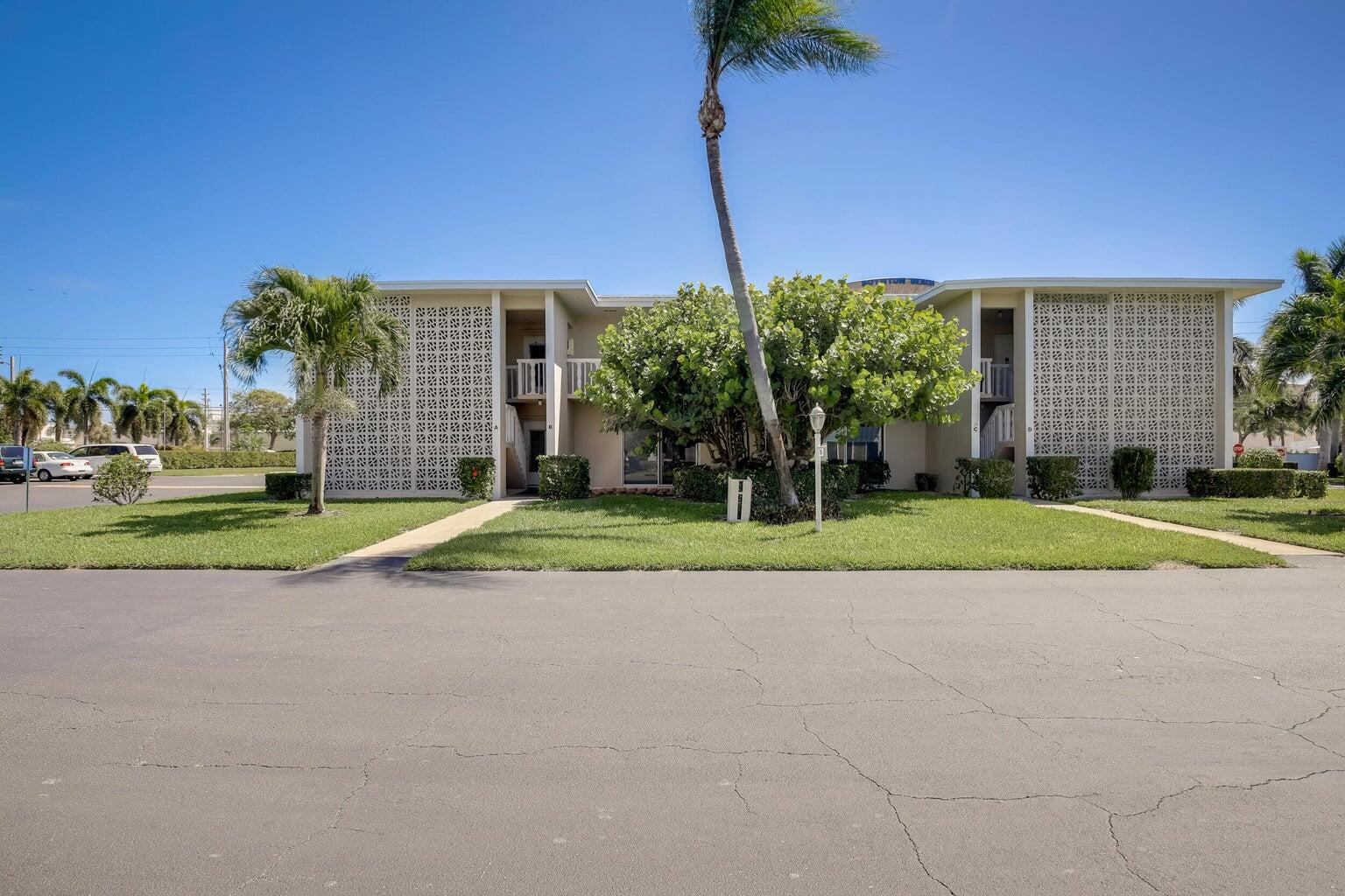 a view of a house with a big yard and palm trees