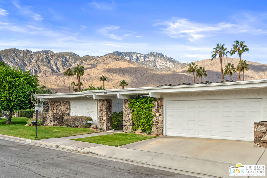 a front view of a house with a yard and mountain view in back