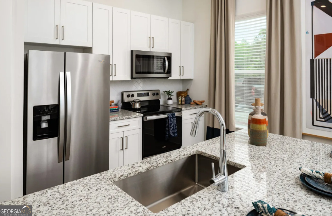 a kitchen with stainless steel appliances kitchen island granite countertop a refrigerator stove and sink