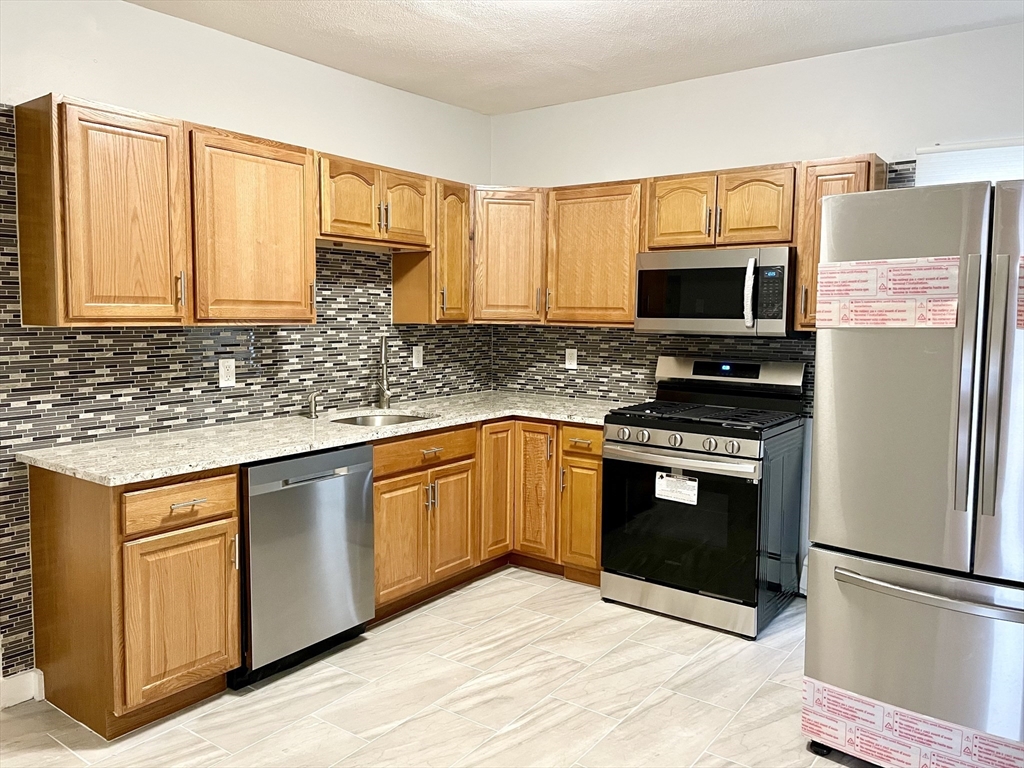 a kitchen with stainless steel appliances granite countertop a stove a sink and a microwave