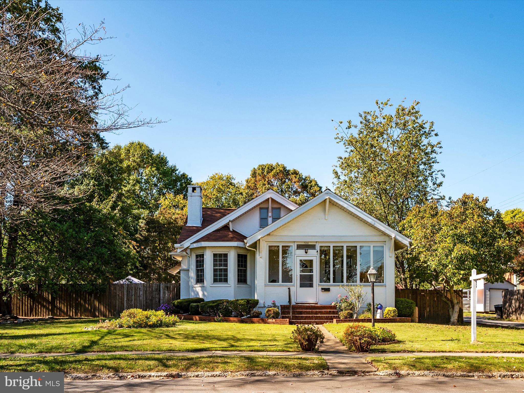 a front view of a house with a garden and trees