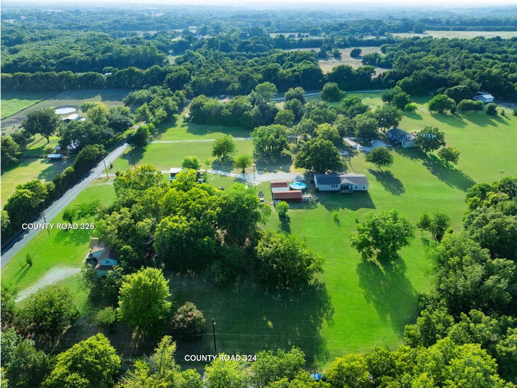 an aerial view of green landscape with trees houses and lake view