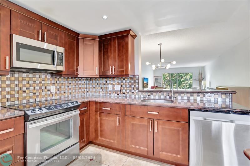 a kitchen with stainless steel appliances granite countertop a stove a sink and a microwave