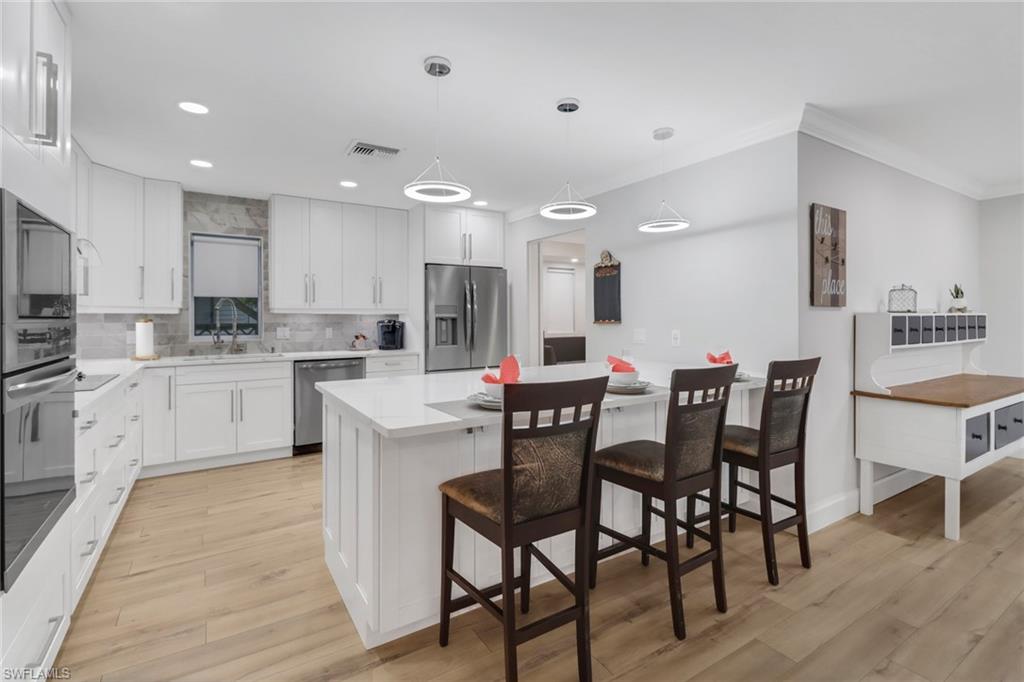 a kitchen with a dining table chairs cabinets wooden floor and appliances