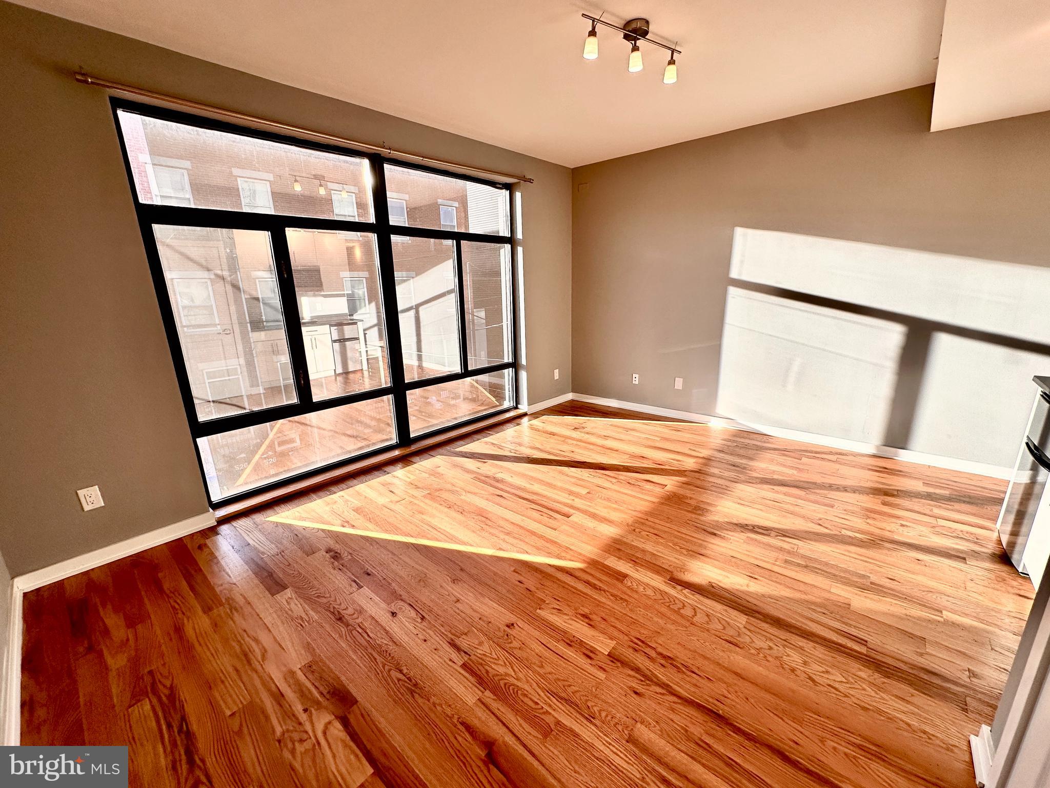 a view of empty room with window and wooden floor