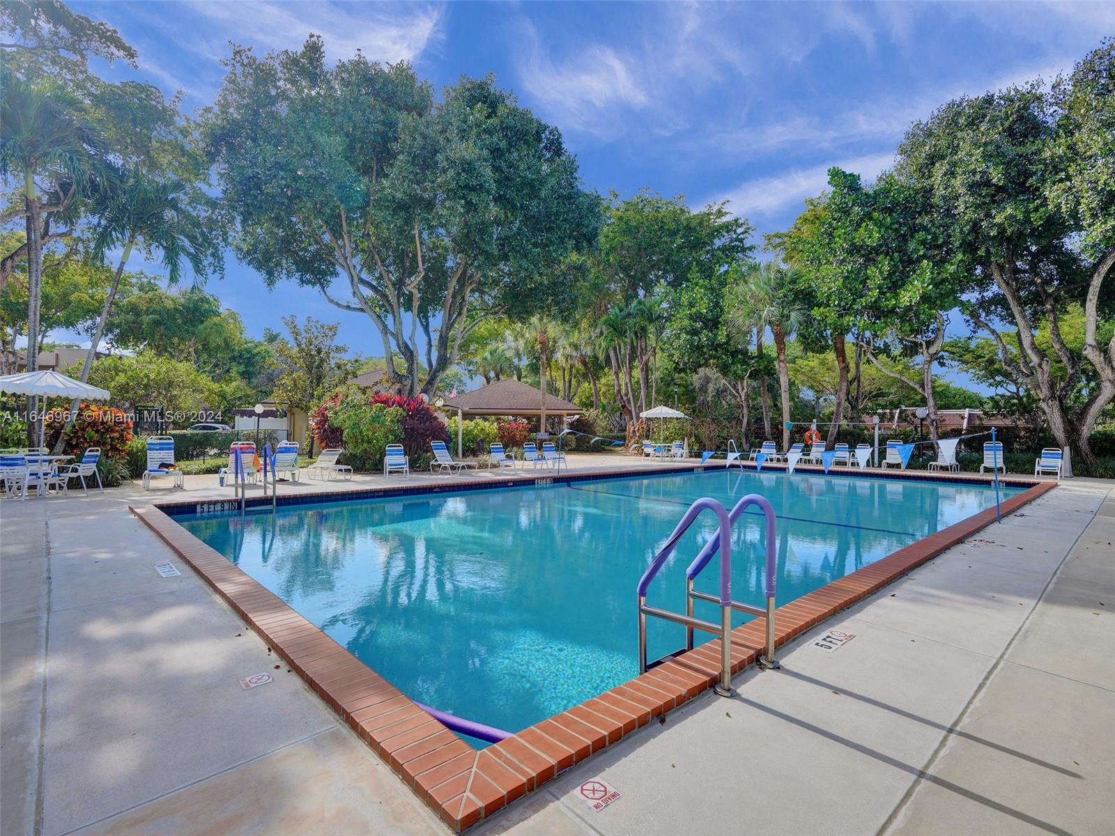 a view of swimming pool with outdoor seating and trees in the background