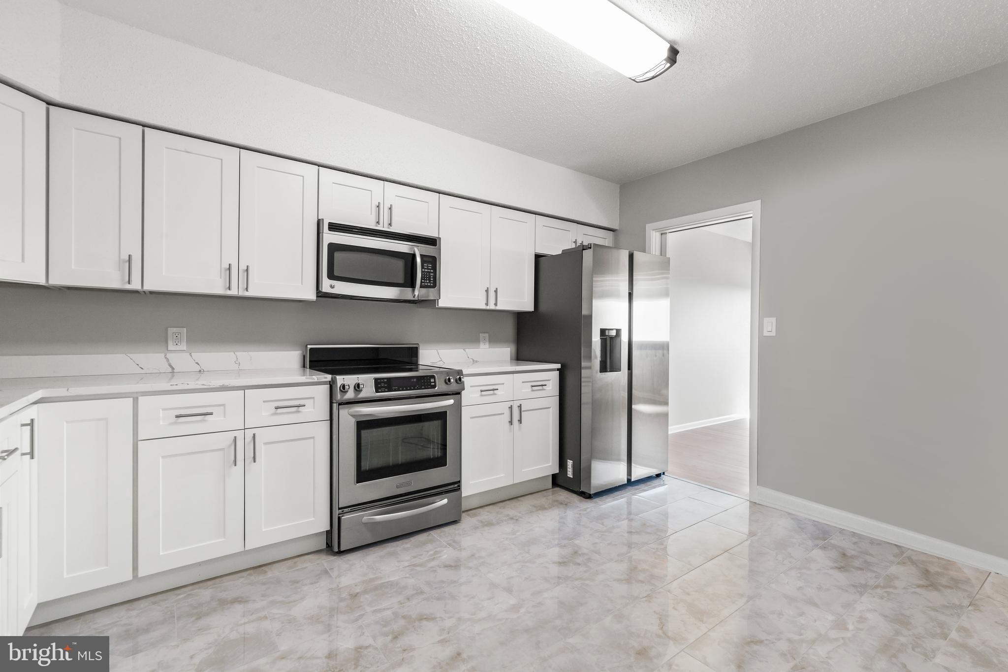 a kitchen with a refrigerator stove and white cabinets