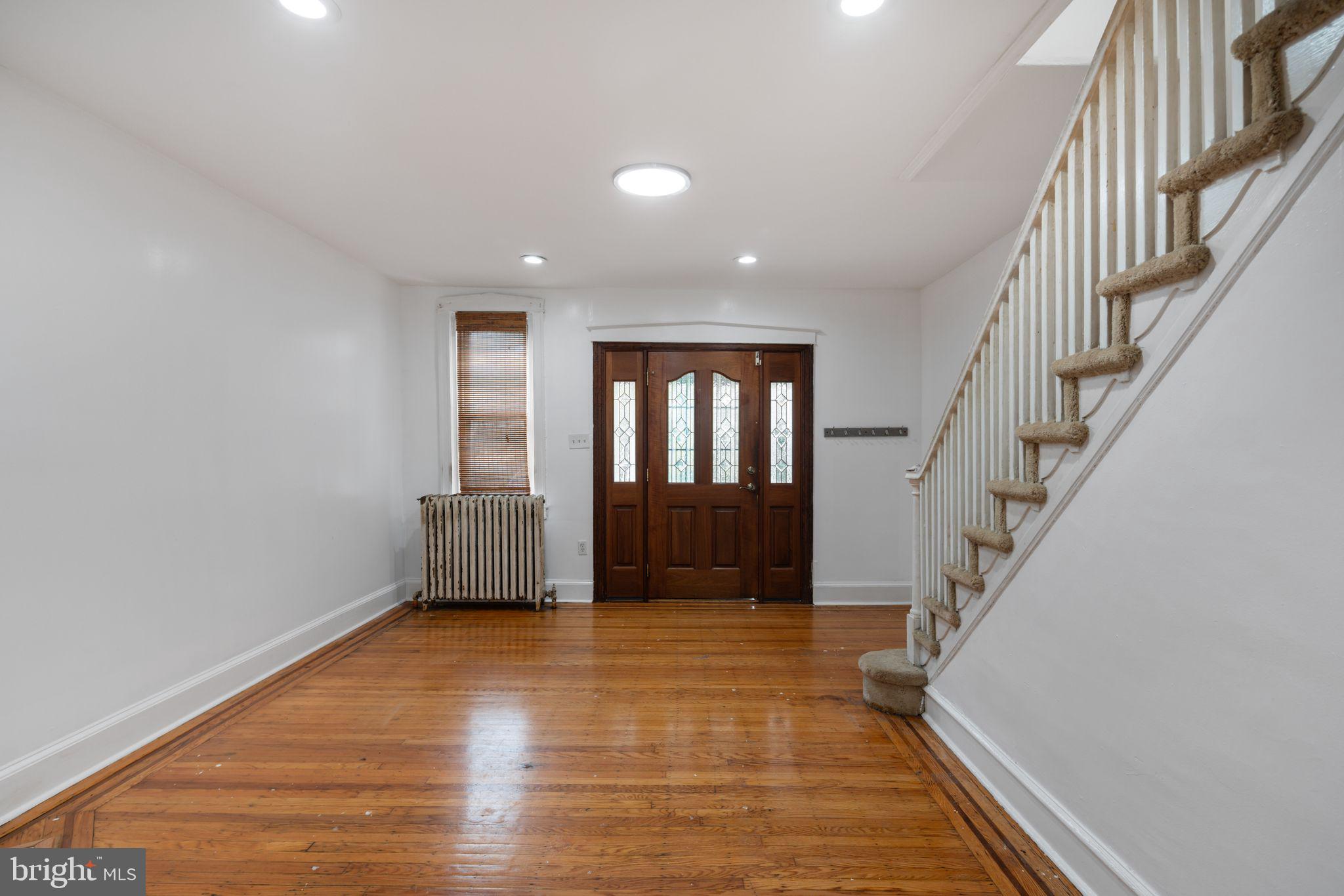 a view of an empty room with wooden floor and stairs