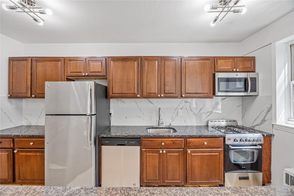 a kitchen with granite countertop a refrigerator stove top oven and sink