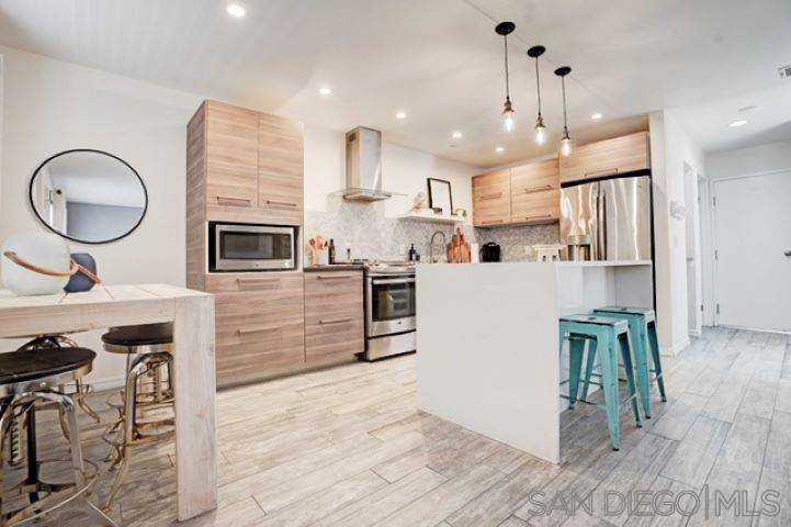 a kitchen with kitchen island a stove a refrigerator and a wooden floor