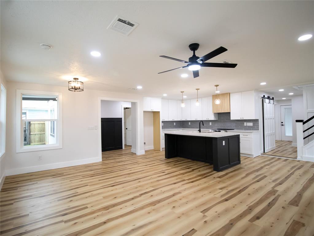 a large kitchen with kitchen island granite countertop a stove cabinets and wooden floor