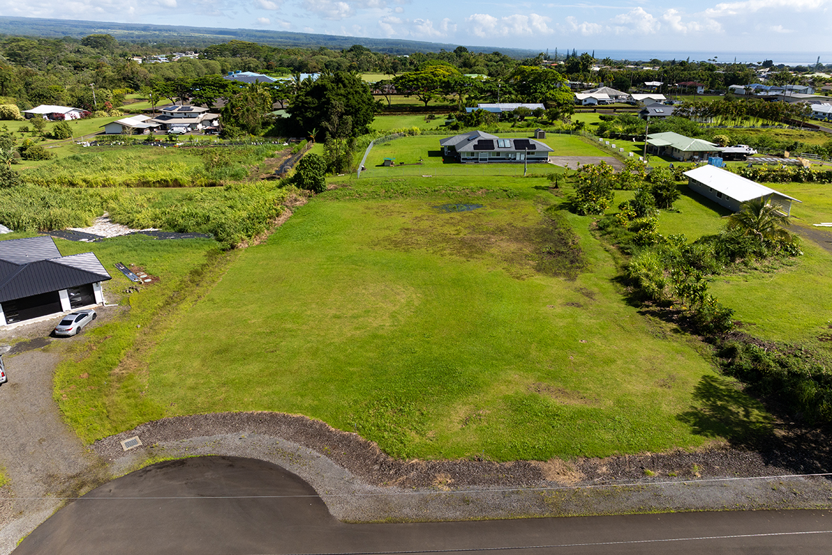 an aerial view of a residential houses with outdoor space and trees all around